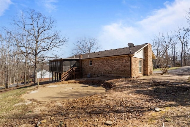 back of house with stairway, brick siding, and a chimney