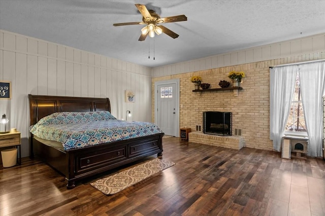 bedroom with visible vents, a textured ceiling, wood finished floors, and a fireplace