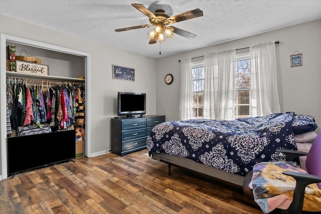 bedroom featuring baseboards, ceiling fan, wood finished floors, a closet, and a textured ceiling