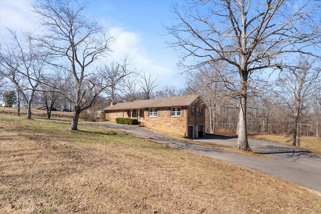 view of front of property with a front yard, brick siding, and driveway