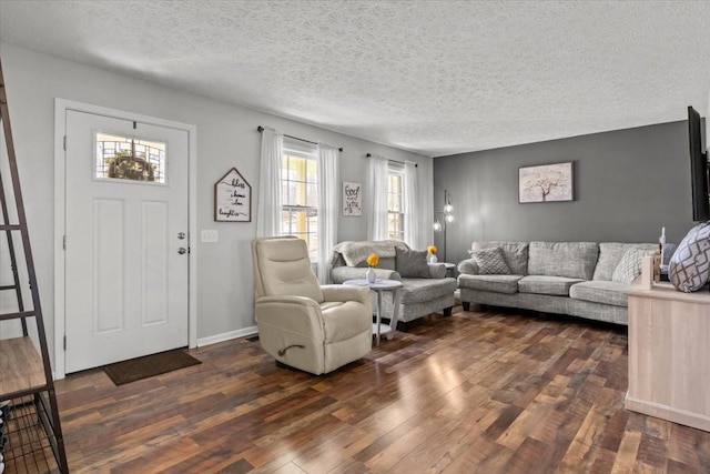 living area with baseboards, dark wood-type flooring, and a textured ceiling