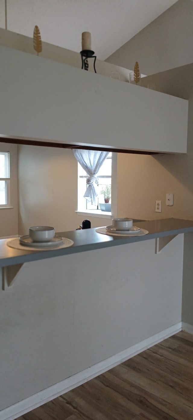 kitchen with a breakfast bar area, baseboards, a peninsula, and dark wood finished floors