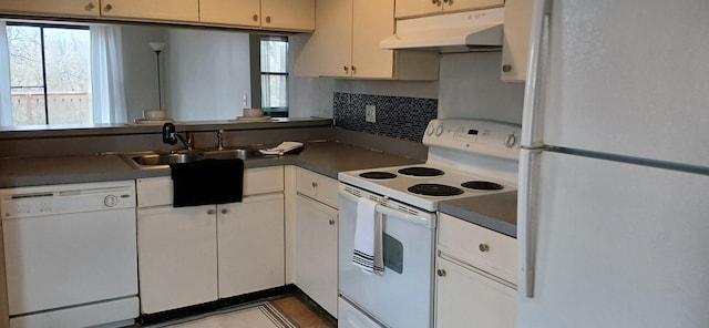 kitchen with white appliances, a sink, decorative backsplash, under cabinet range hood, and dark countertops