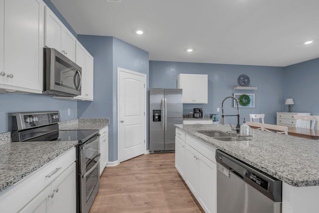 kitchen with a sink, stainless steel appliances, light wood-style flooring, and white cabinetry