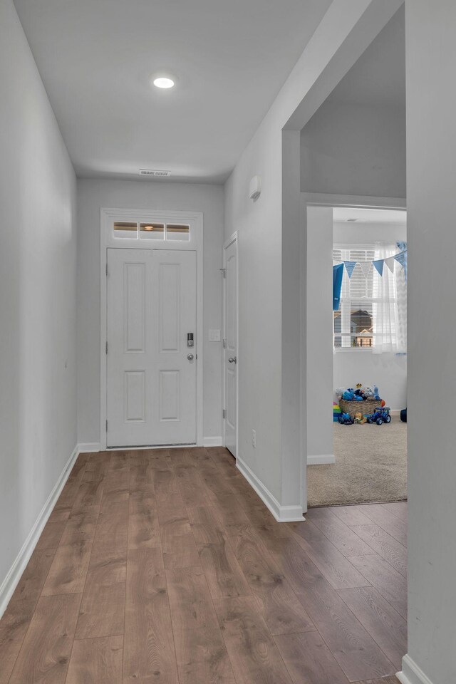 foyer entrance with visible vents, baseboards, and wood-type flooring