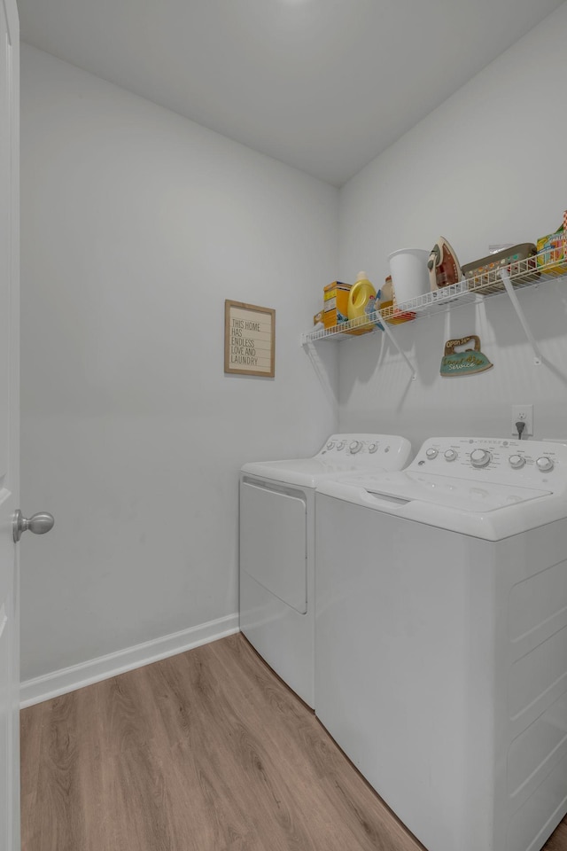 clothes washing area featuring baseboards, independent washer and dryer, wood finished floors, and laundry area