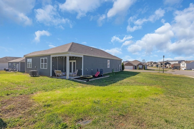 rear view of house featuring a residential view, a lawn, central AC, and a patio area