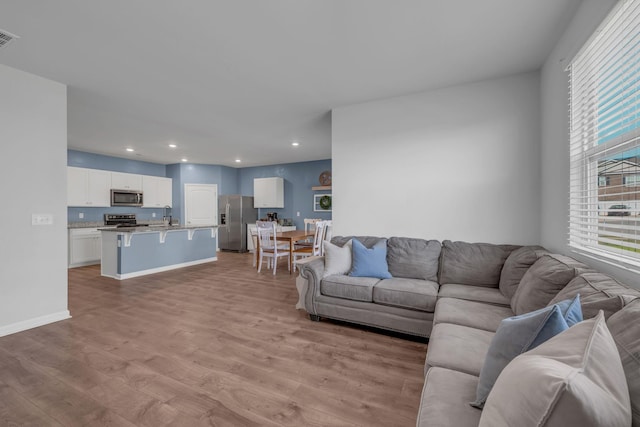 living room with light wood finished floors, visible vents, recessed lighting, and baseboards