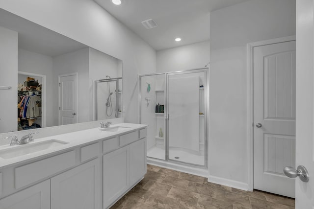 full bathroom featuring double vanity, visible vents, a shower stall, and a sink