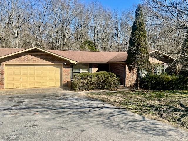 ranch-style home with brick siding, an attached garage, and driveway