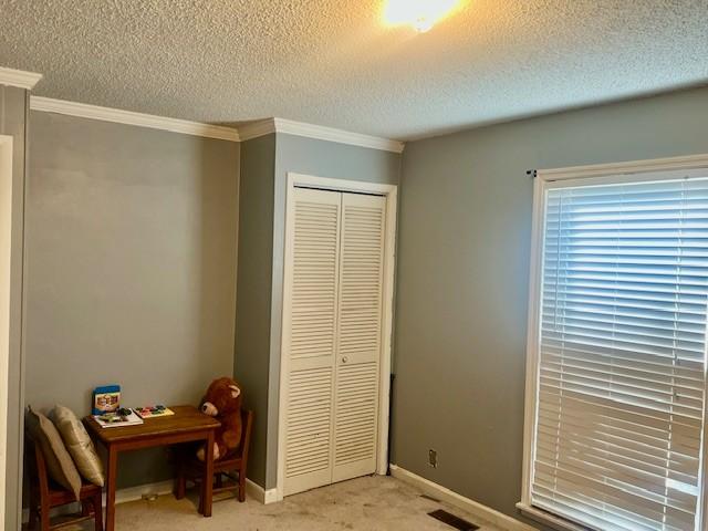 bedroom featuring visible vents, light carpet, ornamental molding, a closet, and baseboards