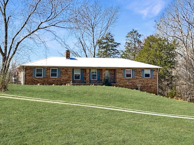 ranch-style house featuring a front yard, brick siding, and a chimney