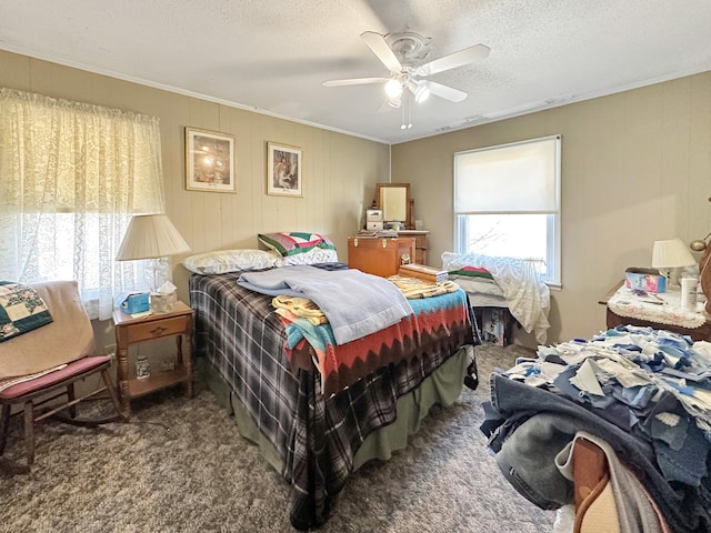 bedroom featuring a textured ceiling, ceiling fan, carpet flooring, and ornamental molding