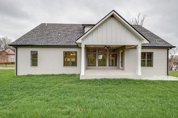 back of house with a yard, a shingled roof, a ceiling fan, and a patio area