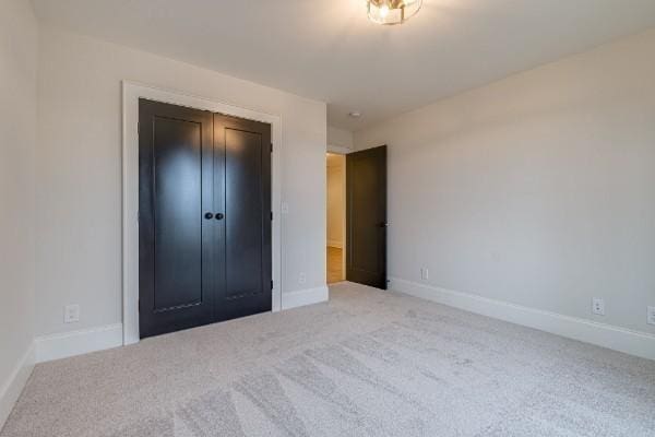 unfurnished bedroom featuring carpet flooring, baseboards, and a closet