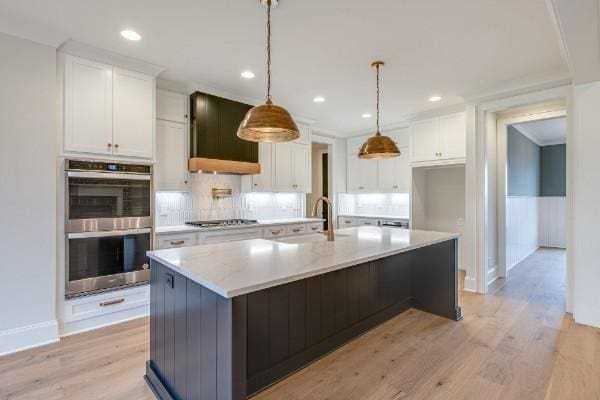 kitchen featuring a sink, appliances with stainless steel finishes, light wood-style flooring, and white cabinetry