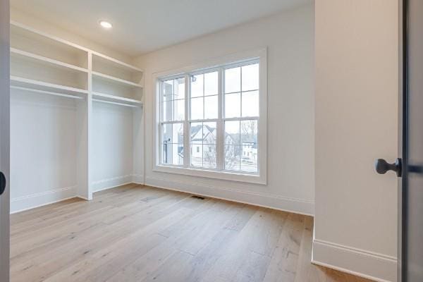 unfurnished bedroom featuring a closet, multiple windows, baseboards, and wood finished floors