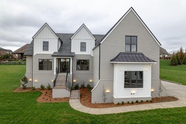 modern farmhouse style home featuring metal roof, board and batten siding, a front yard, and a standing seam roof