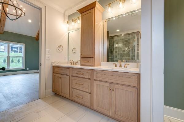 full bath featuring double vanity, a notable chandelier, a shower stall, and a sink