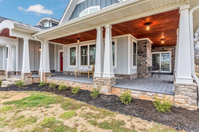 entrance to property featuring a porch, stone siding, and board and batten siding