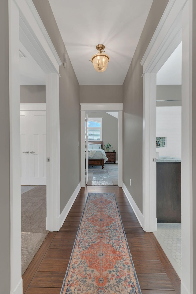 corridor with baseboards and wood finished floors