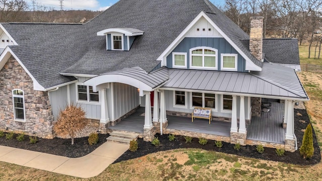 view of front of home with a standing seam roof, a porch, board and batten siding, a shingled roof, and metal roof