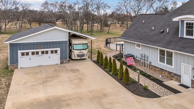 view of property exterior featuring roof with shingles, concrete driveway, stone siding, a garage, and board and batten siding