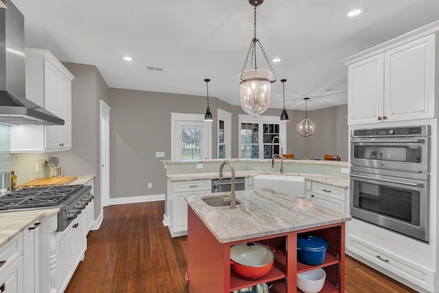 kitchen featuring a sink, open shelves, stainless steel appliances, a peninsula, and wall chimney exhaust hood