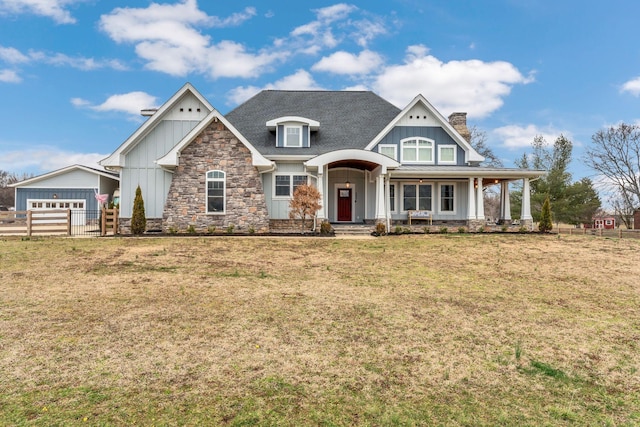 craftsman inspired home with a front yard, fence, board and batten siding, and stone siding