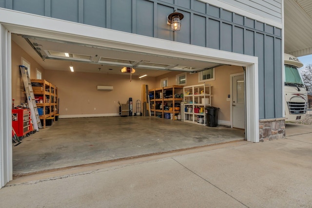 garage with an AC wall unit, a garage door opener, and driveway