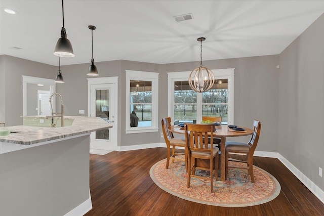 dining area with visible vents, baseboards, dark wood-type flooring, and an inviting chandelier