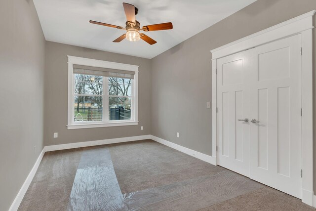 carpeted empty room with a ceiling fan and baseboards