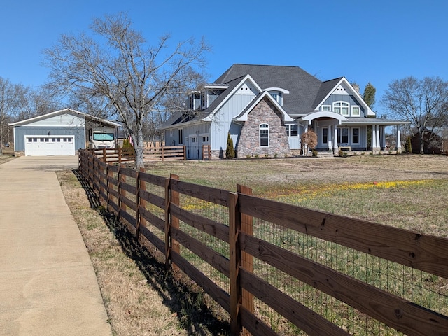 exterior space with a front lawn, stone siding, fence, board and batten siding, and a shingled roof