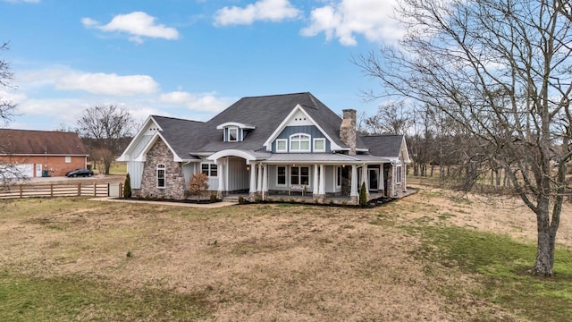 view of front of property with a standing seam roof, a porch, fence, a front yard, and metal roof