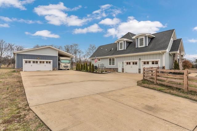 exterior space with fence, driveway, a shingled roof, stone siding, and board and batten siding