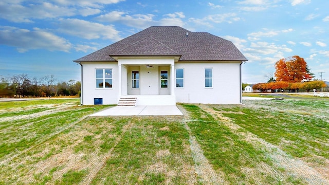 rear view of house with a patio area, a lawn, a shingled roof, and ceiling fan