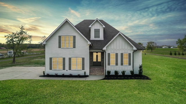 view of front of property with a lawn, board and batten siding, driveway, and a shingled roof