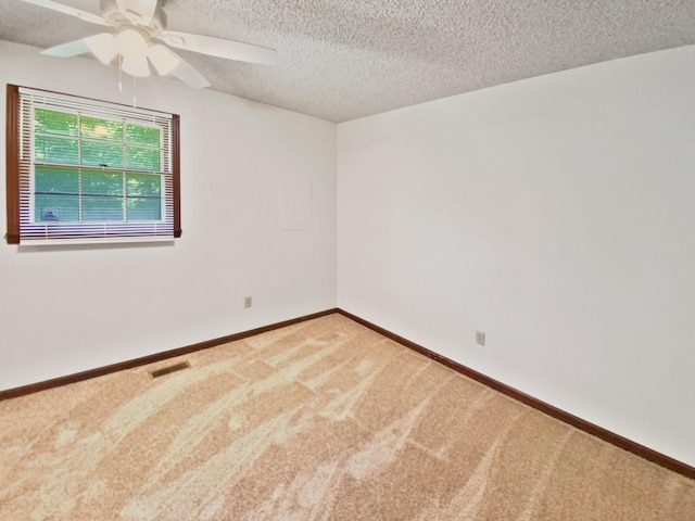 carpeted empty room featuring visible vents, a textured ceiling, baseboards, and a ceiling fan