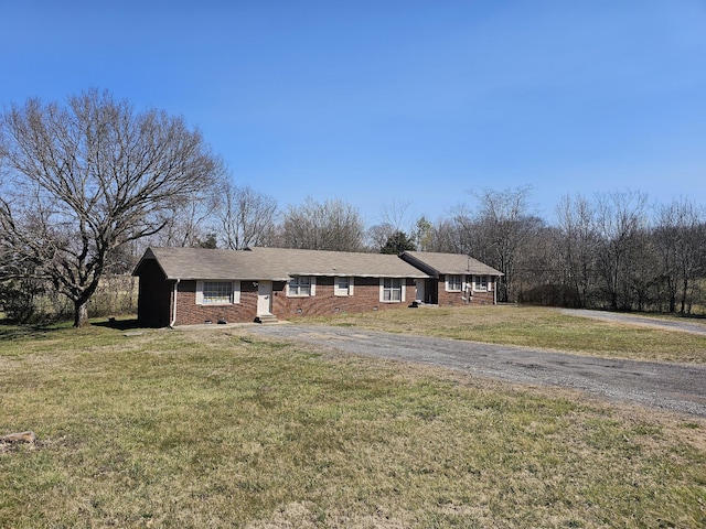 ranch-style home with driveway, brick siding, and a front yard