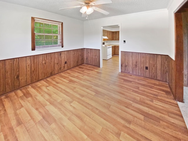 empty room with a textured ceiling, wooden walls, and wainscoting