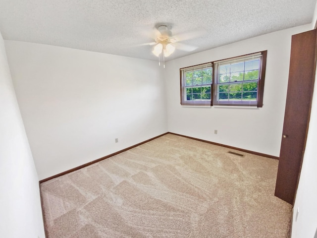 empty room with a textured ceiling, carpet, visible vents, and baseboards