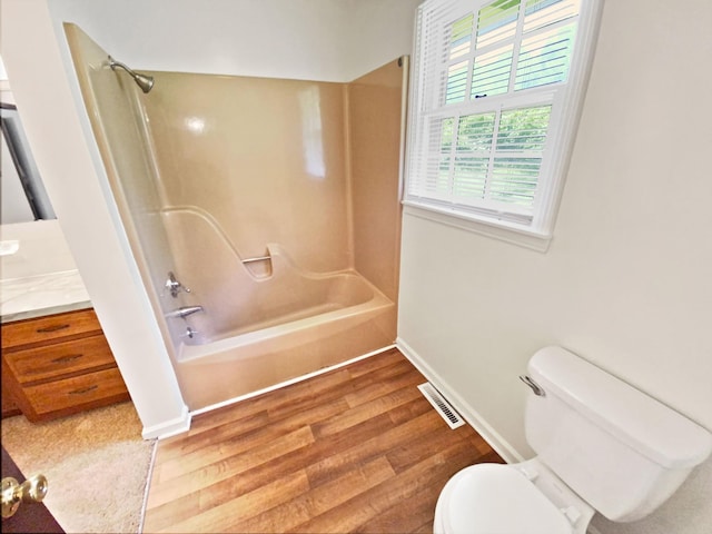 bathroom featuring visible vents, toilet, wood finished floors, tub / shower combination, and vanity