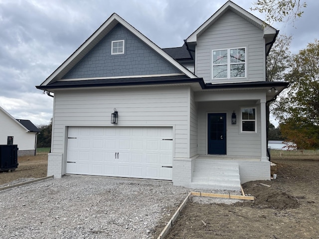 view of front of property featuring brick siding, gravel driveway, and an attached garage