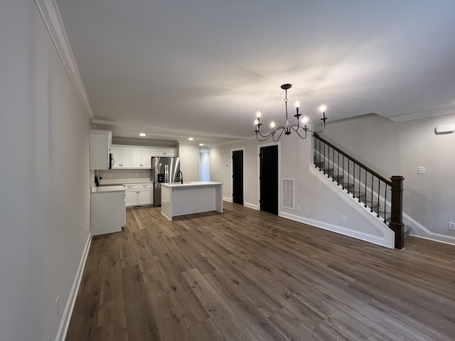 unfurnished living room featuring dark wood-style floors, baseboards, ornamental molding, stairs, and a chandelier