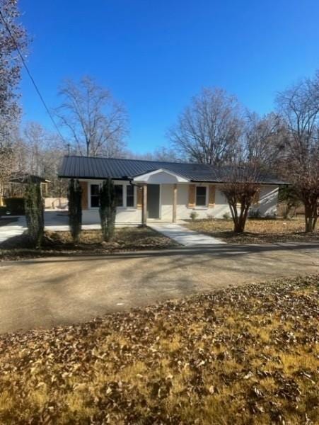 ranch-style house with metal roof and driveway