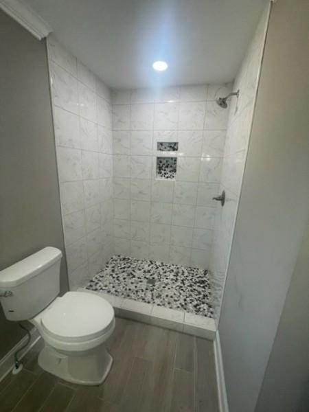 full bathroom featuring wood finish floors, baseboards, toilet, and a shower stall