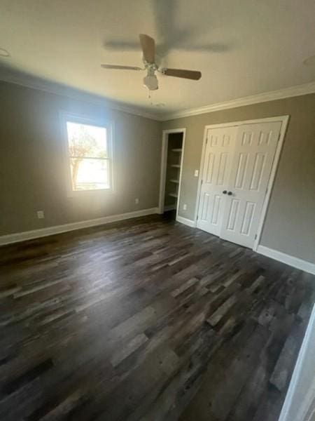 unfurnished bedroom with baseboards, dark wood-style floors, and crown molding