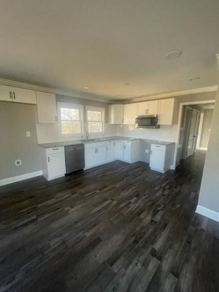 kitchen featuring ornamental molding, a sink, stainless steel appliances, white cabinets, and baseboards