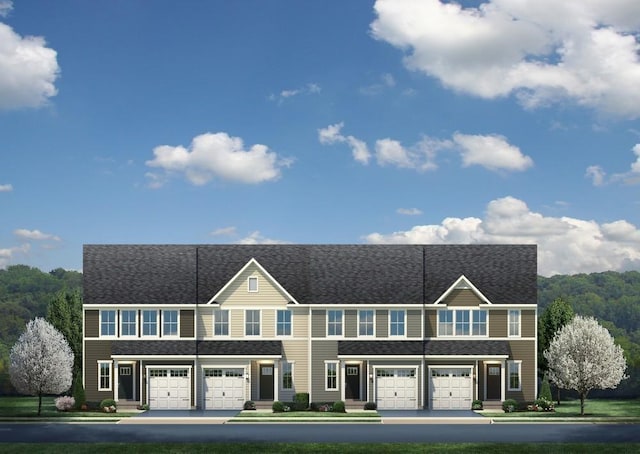 view of property featuring a front lawn, an attached garage, and driveway