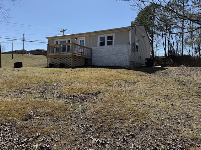 exterior space with stone siding, central air condition unit, and a wooden deck